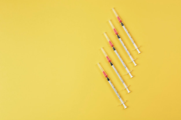 Foto grupo de seringas em fundo amarelo. conceito de vacina e injeções de coronavírus. vacina contra gripe.