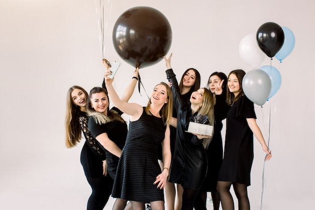 Grupo de sete melhores amigas de meninas fazendo selfie em smartphone, aproveitando a festa de aniversário com balões de bolo e ar, se divertindo, sorrindo e rindo. amizade e conceito de festa de aniversário