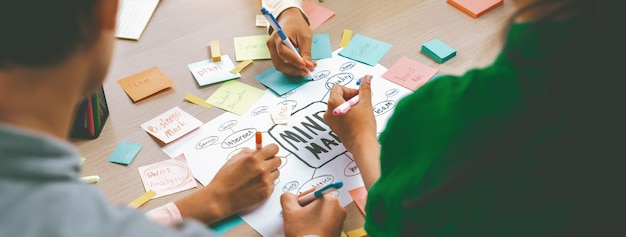 Foto grupo de startups profissionais compartilham idéia de marketing criativa usando mapa mental jovens empresários qualificados fazem brainstorming de plano de negócios enquanto escrevem notas adesivas foco na mão closeup variado