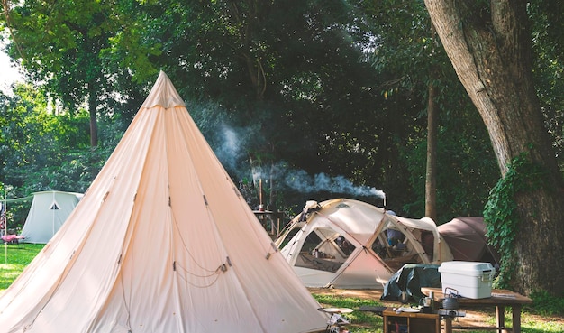 Grupo de tendas de campo com equipamento de cozinha ao ar livre na área de acampamento no parque natural na hora da manhã