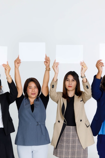 Grupo de tiro de estúdio de funcionários de escritório feminino em negócios usa suporte segurar rosto de capa de sinal de papel vazio em branco para texto de anúncio em fundo branco.