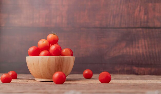 Foto grupo de tomates maduros em uma tigela de madeira colocada na mesa de madeira