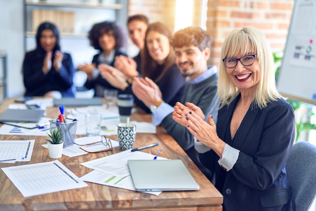 Grupo de trabalhadores de negócios sorrindo felizes e confiantes. Trabalhando juntos com sorriso no rosto olhando para a câmera aplaudindo no escritório