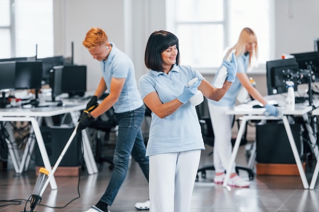 Grupo de trabalhadores limpa escritório moderno juntos durante o dia