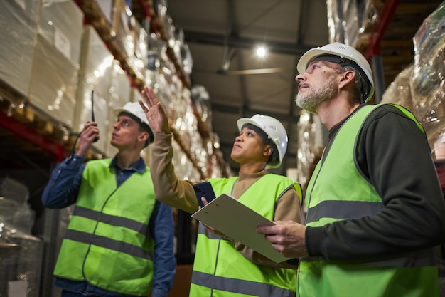 Grupo de trabalhadores no armazém fazendo gerenciamento de armazenamento de revisão de estoque