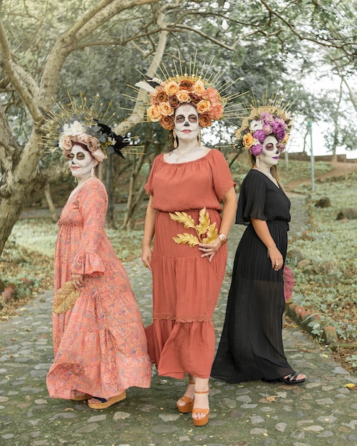 Foto grupo de três mulheres mostrando catrinas compõem. maquiagem para a celebração do dia dos mortos.