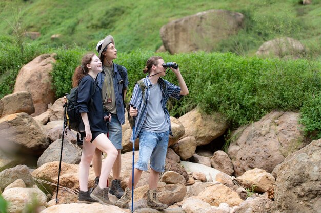 Grupo de turistas com mochilas caminhando na trilha no rio e nas montanhas