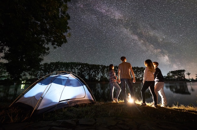 grupo de turistas com tenda na margem do lago à noite