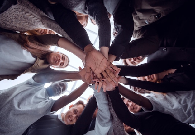 Grupo de vista inferior de jovens felizes fazendo uma pilha de mãos