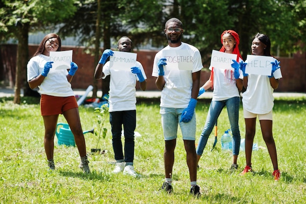 Grupo de voluntários africanos felizes segura placa em branco com sinal juntos no parque áfrica voluntariando pessoas de caridade e conceito de ecologia