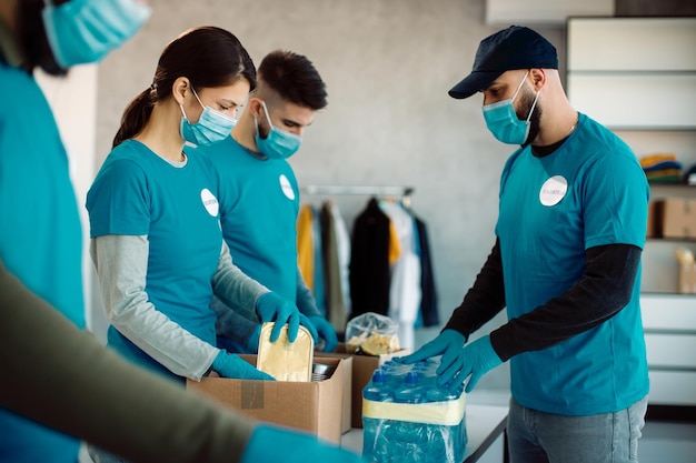 Grupo de voluntários embalando caixas de doação com alimentos e bebidas para caridade