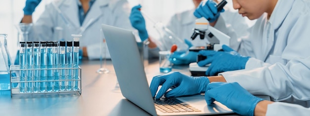 Un grupo dedicado de científicos lleva a cabo experimentos químicos e investigaciones en el laboratorio médico como un desarrollo innovador para un nuevo fármaco de vacuna o antibiótico y estudia el resultado de la prueba en la computadora portátil Neoteric