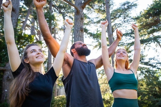 Un grupo de deportistas están felices con sus manos levantadas en el aire durante un entrenamiento estilo de vida saludable