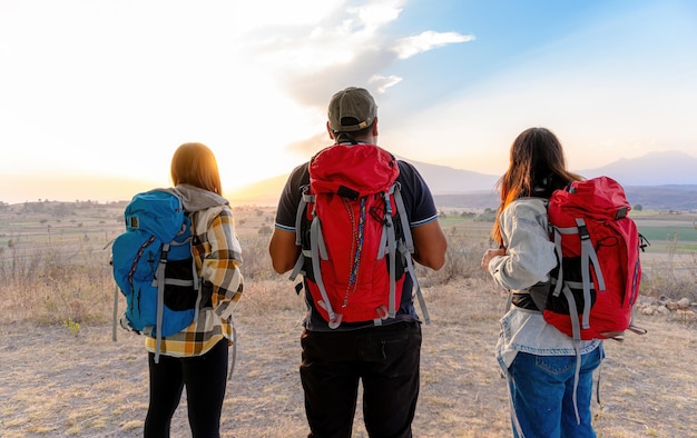 Grupo de deportistas en las montañas viendo la puesta de sol con mochilas concepto de senderismo libertad de viaje exploración cumbre caminata