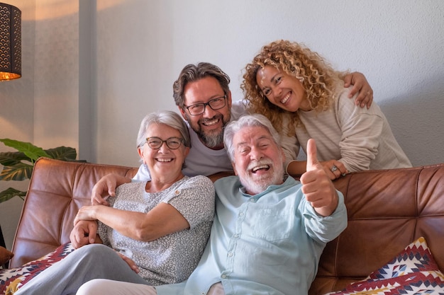 Grupo despreocupado de uma família de várias gerações sentada no sofá em casa relaxando e passando um tempo juntos