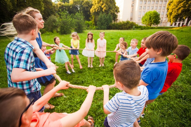 Un grupo de diferentes niños y un cuidador forman un círculo de cuerda en el parque