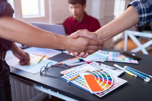 Foto un grupo de diseñadores asiáticos se dio la mano después de reunirse después de elegir el color del producto terminado.