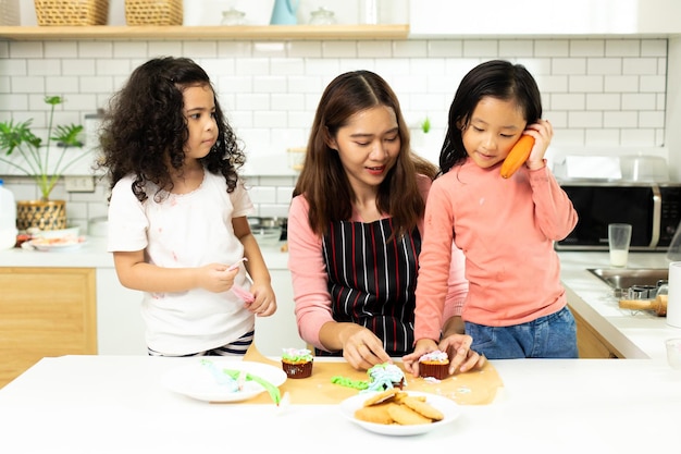 Grupo de diversas familias asiáticas y árabes preescolares africanos niños árabes hacen pastel cocinando en la cocina La madre prepara la decoración bonita con diversión educar sobre la merienda Lío de crema en todo el espacio de la copia de la cara