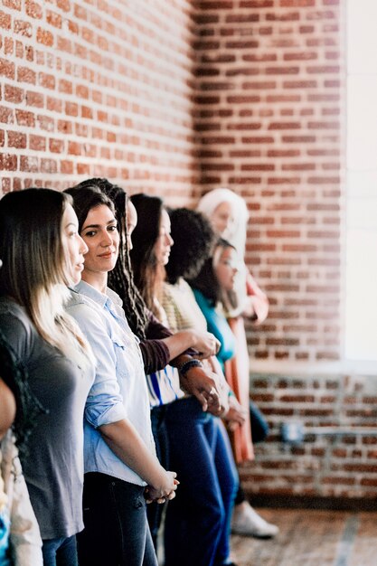 Grupo de diversas personas de pie delante de una pared de ladrillos