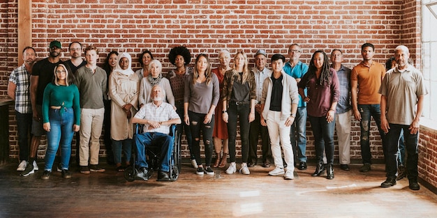 Grupo de diversas personas de pie frente a una pared de ladrillos