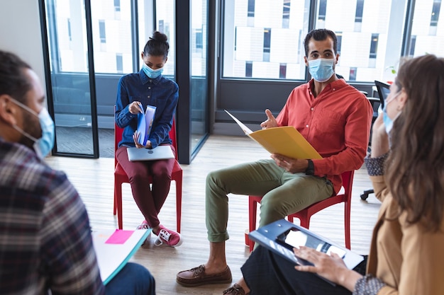 Grupo diversificado de colegas criativos usando máscaras falando na reunião. trabalhar em um escritório moderno durante a pandemia de coronavírus covid 19.