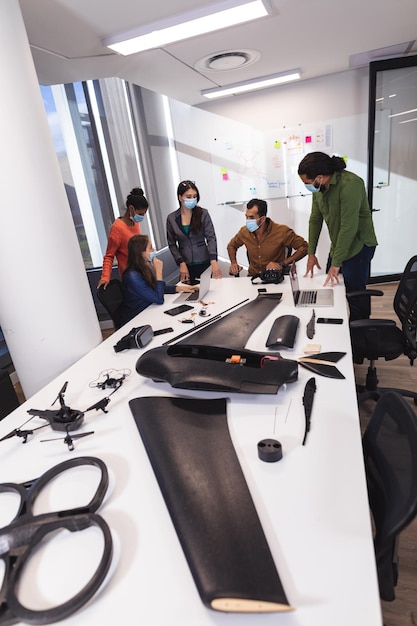 Foto grupo diversificado de colegas criativos usando máscaras falando na reunião. trabalhar em um escritório moderno durante a pandemia de coronavírus covid 19.