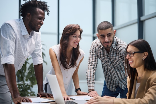 Foto grupo diversificado de colegas de trabalho ouvindo uma apresentação durante uma reunião de equipe em torno de uma mesa em um escritório