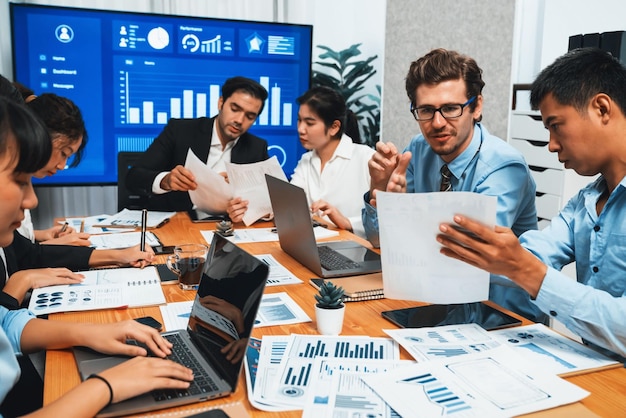 Grupo diversificado de equipe de analistas de negócios analisando relatório de dados financeiros Gráfico de análise de dados financeiros e painel de gráficos no ecrã da TV na sala de reuniões para planejamento de marketing estratégico Habiliment