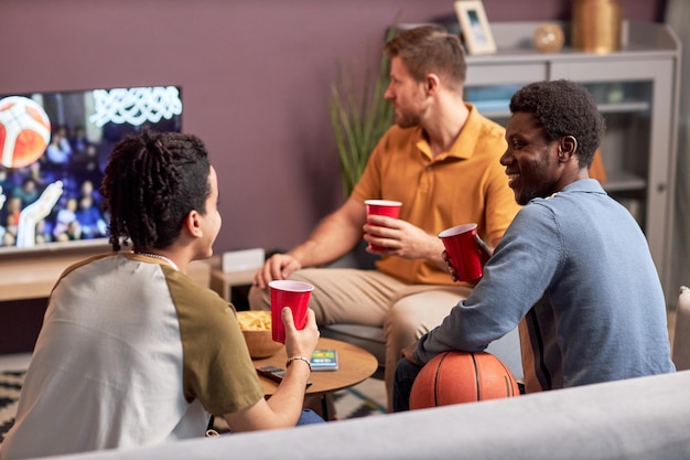 Grupo diversificado de homens assistindo jogo de esportes na TV