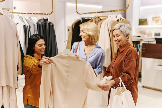 Grupo diversificado de mulheres comprando roupas em boutique e procurando blusas