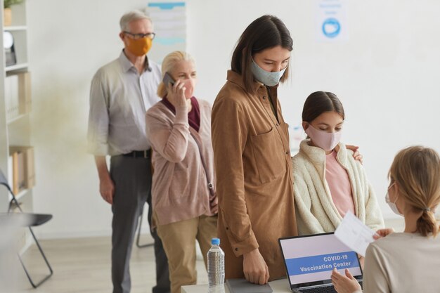 Grupo diversificado de pessoas esperando na fila enquanto se registram para a vacina covid no centro médico, copie o espaço