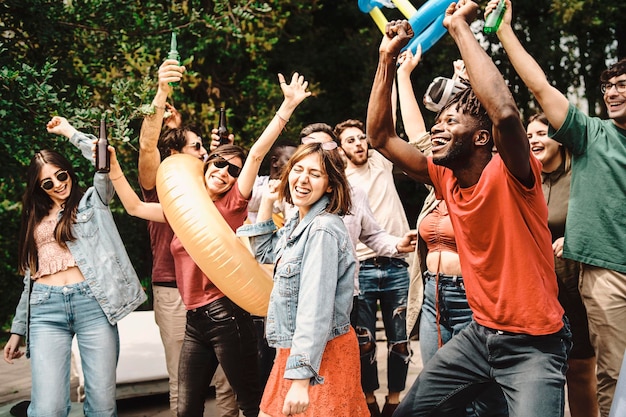 Grupo diversificado e brincalhão de jovens dançando e socializando juntos na festa diurna no jardim Família alegre multigeracional curtindo suas férias ao ar livre Foco no homem africano