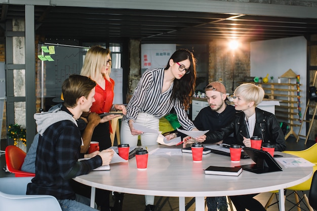 Grupo diversificado multiétnico de equipe criativa, empresários casuais ou estudantes universitários em reunião estratégica ou discussão de projeto no escritório, usando tablets. Conceito de inicialização ou trabalho em equipe.