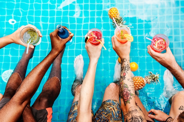 Un grupo diverso de amigos disfrutando el horario de verano con bebidas en las manos
