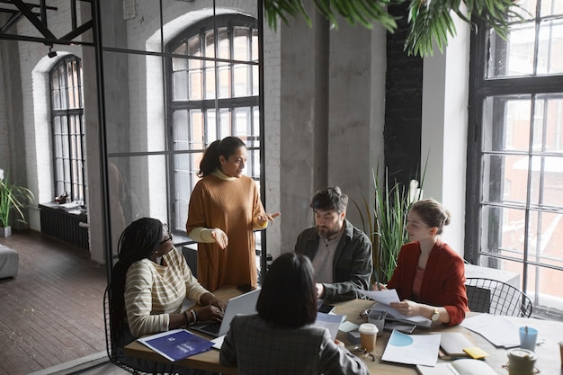 Grupo diverso de gente de negocios que colabora en la mesa de reuniones en el interior de la oficina gráfica, espacio de copia