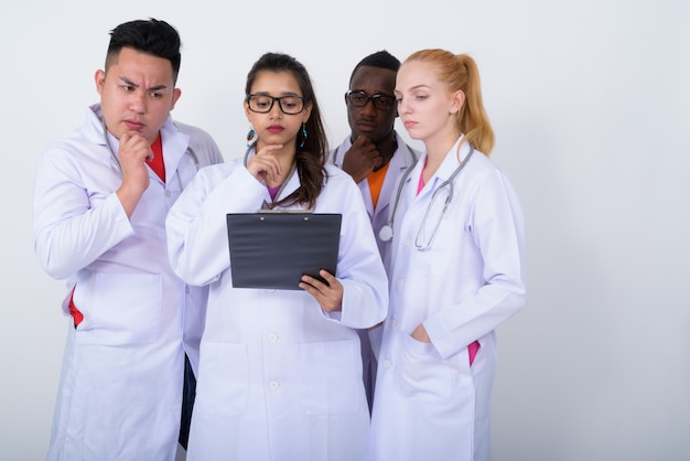 Foto grupo diverso de médicos multiétnicos pensando mientras lee desde un portapapeles