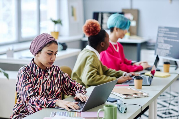 Grupo diverso de mujeres musulmanas creativas usando laptop