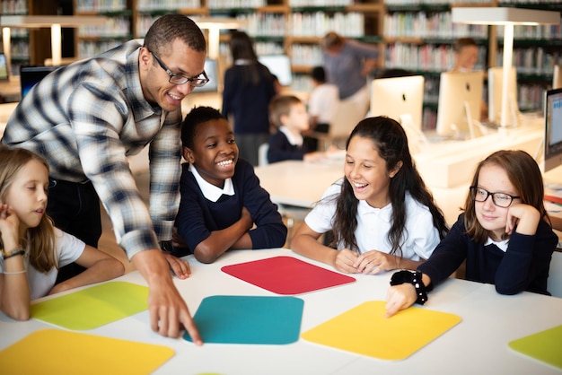 Un grupo diverso de niños y un maestro en un aula comprometidos y sonrientes Aprendizaje en el aula Interacción de grupo diverso y maestro Concepto escolar de aprendizaje de educación con espacio de copia