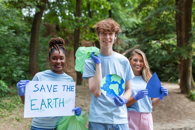 Grupo diverso de personas recogiendo basura en el parque Servicio comunitario voluntario Voluntarios internacionales felices sosteniendo pancartas con el mensaje 'Salvar la Tierra'