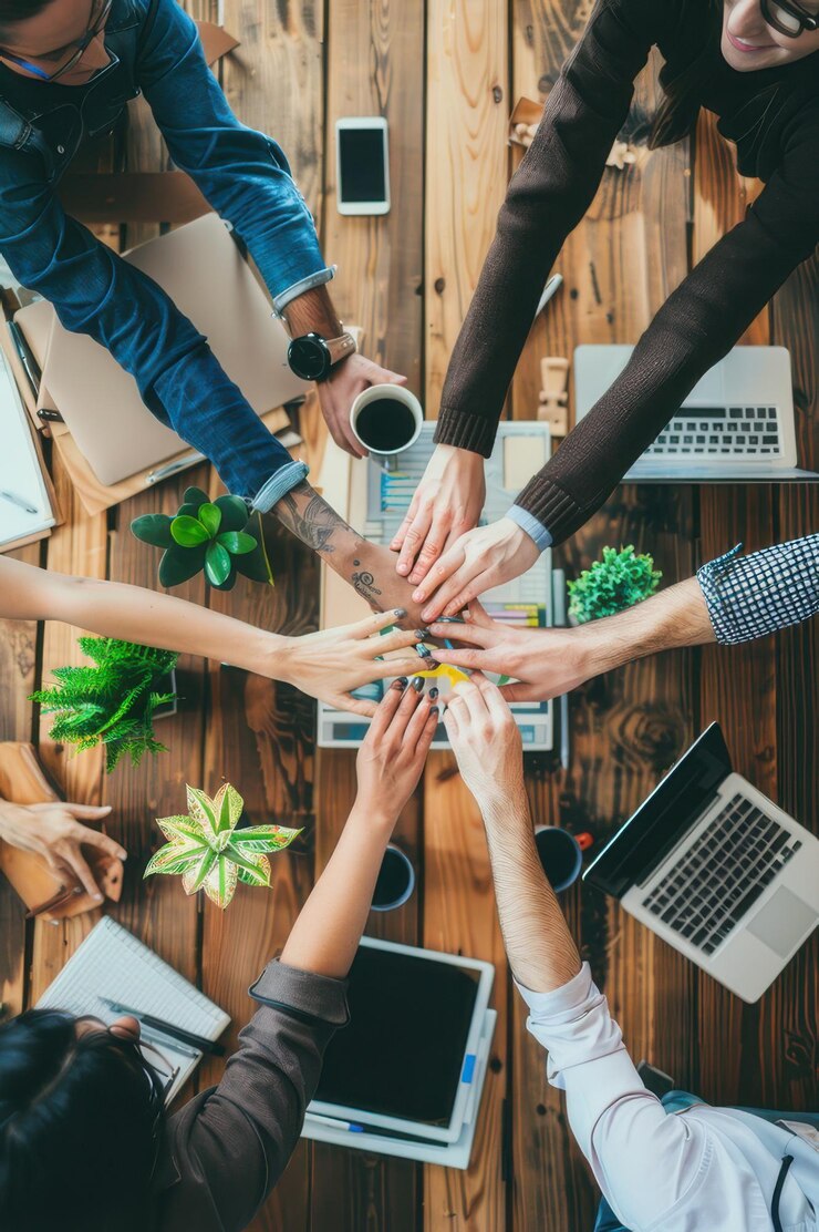 Un grupo diverso de profesionales juntando sus manos en unidad simbolizando el trabajo en equipo, la colaboración y el éxito.