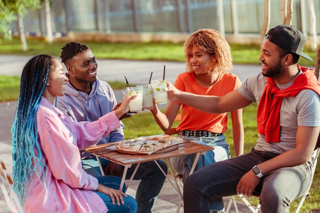 Grupo de diversos amigos afroamericanos sonrientes reunidos en una fiesta de cumpleaños sentados en un café