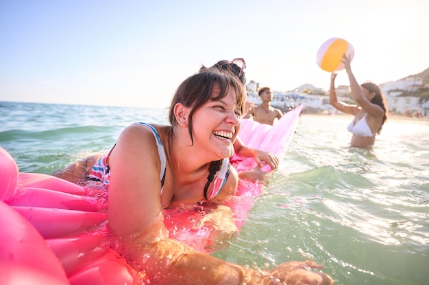Un grupo de diversos amigos jóvenes en trajes de baño disfrutando en el mar en la playa y jugando