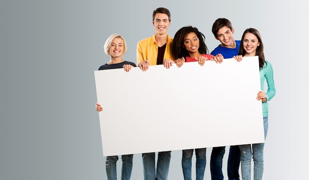 Grupo de diversos jóvenes felices diferentes mantenga con un cartel rectangular blanco en blanco