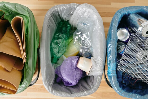 Un grupo de diversos tipos de basura en bolsas de plástico sobre la mesa de madera