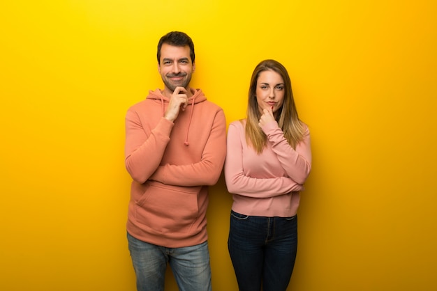 Grupo de dos personas sobre fondo amarillo sonriendo y mirando al frente