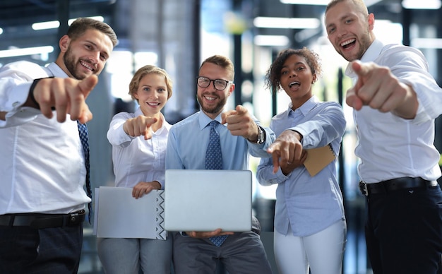 Un grupo de empleados exitosos apuntando hacia ti.