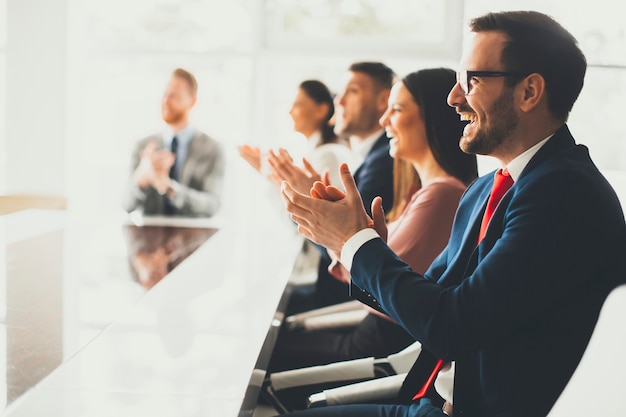 Grupo empresarial sonriente aplaudiendo las manos en la reunión