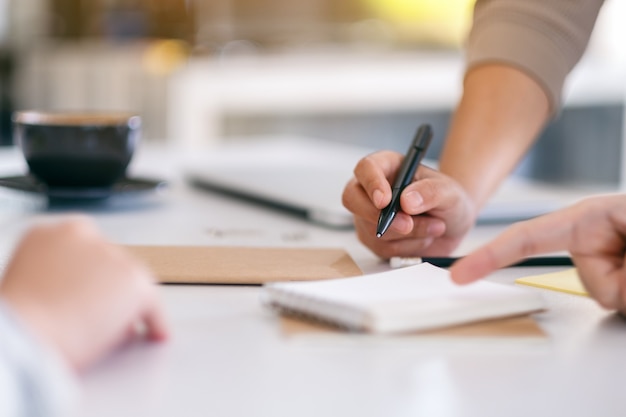 Grupo de empresario discutiendo y escribiendo en el cuaderno sobre la mesa en la oficina