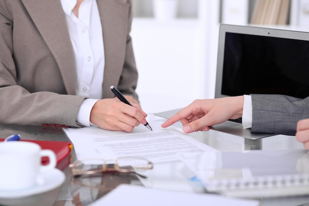 Grupo de empresarios y abogados discutiendo contratos sentados en la mesa. Jefe mujer está firmando papeles