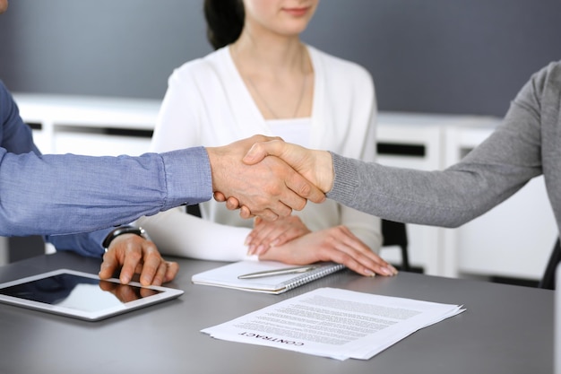 Grupo de empresarios dándose la mano después de discutir preguntas y lograr un acuerdo en una reunión en una oficina moderna. Primer plano de apretón de manos. Trabajo en equipo, asociación y concepto de negocio.